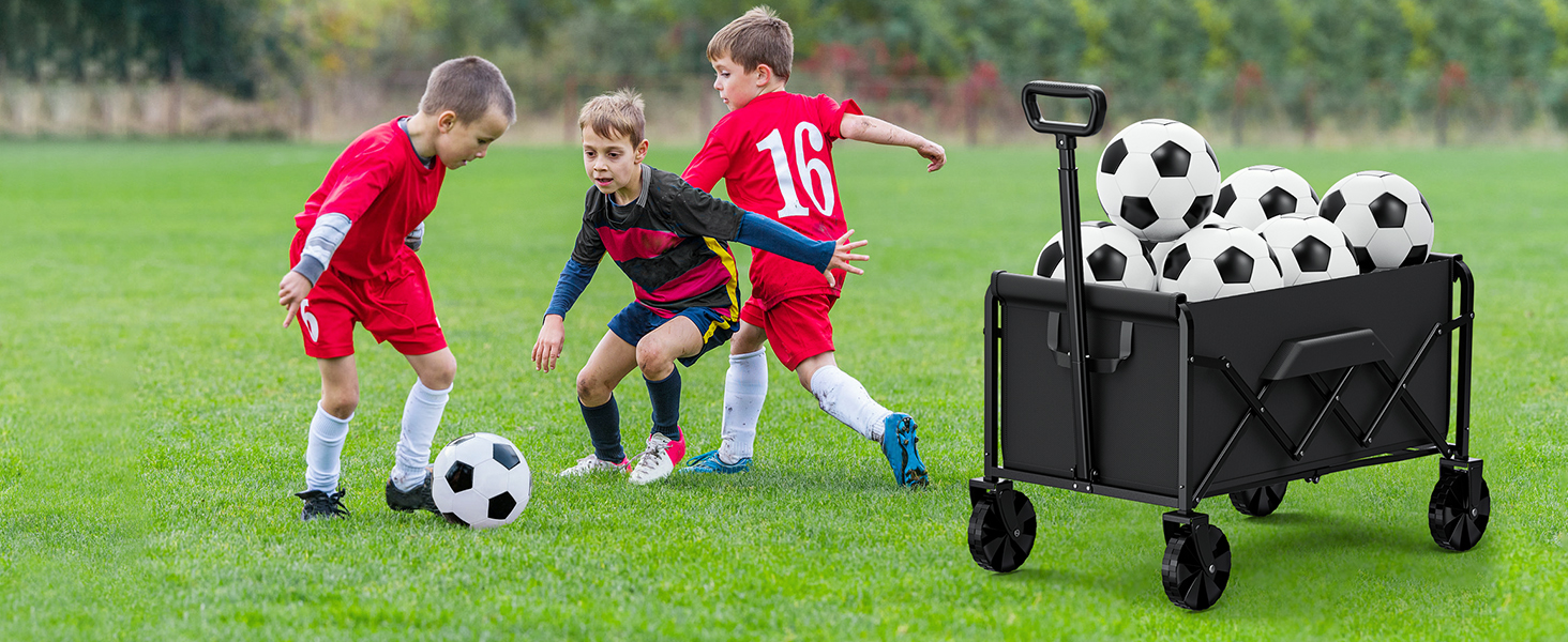 Soccer players in action on grass field. Black collapsible utility wagon visible on sideline filled with soccer balls.