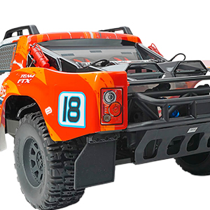 Underwater or action camera mounted on orange base/harness. Device features lens and mounting bracket visible in close-up. Orange protective housing suggests durability for extreme sports or water sports use.