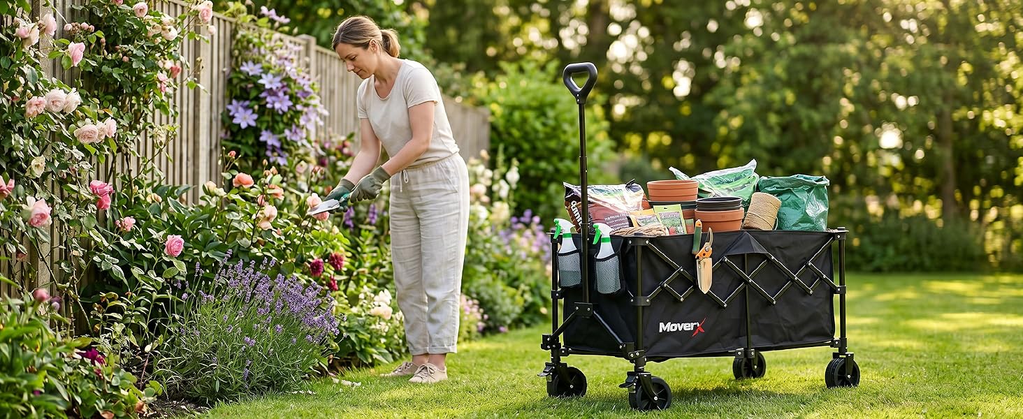 Person using garden tool to work on purple flowering plants near black wheeled garden cart on grass with trees in background.