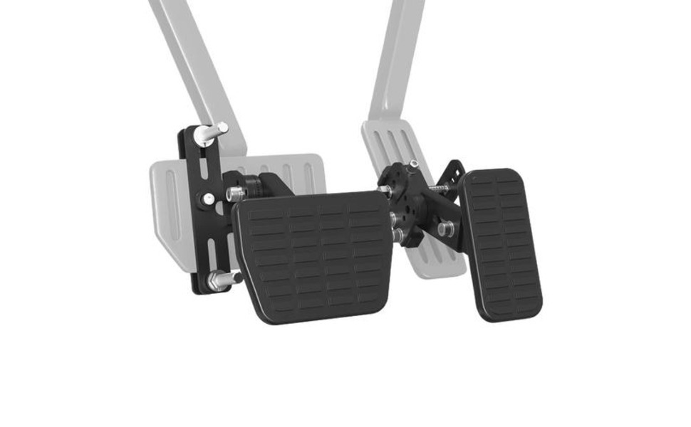 Automotive pedal extension kit featuring black textured foot plates with adjustable mounting bracket, shown above a partial view of a white electric vehicle.