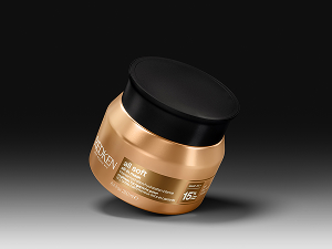 Golden-brown glass bottle with 'REDKEN' brand text visible against dark background. Professional hair care product with metallic amber-colored liquid inside.