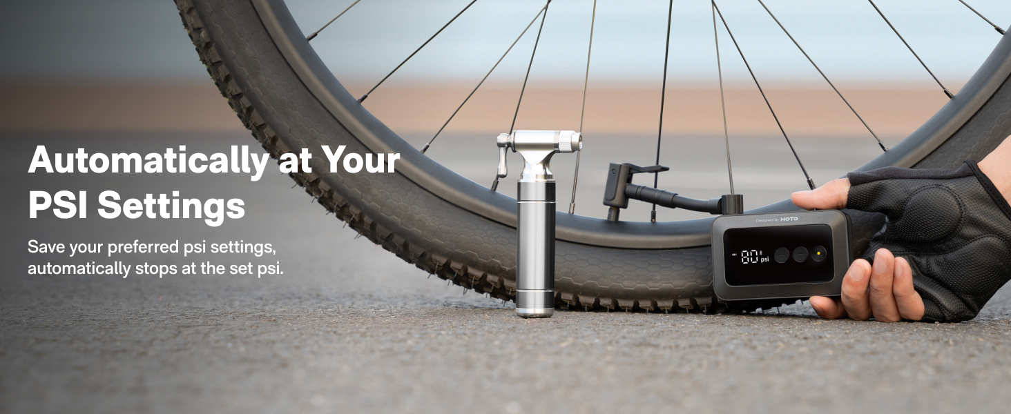 Portable air compressor inflating bicycle tire. Digital display shows PSI. Hand holding device, demonstrating automatic inflation to preset pressure.
