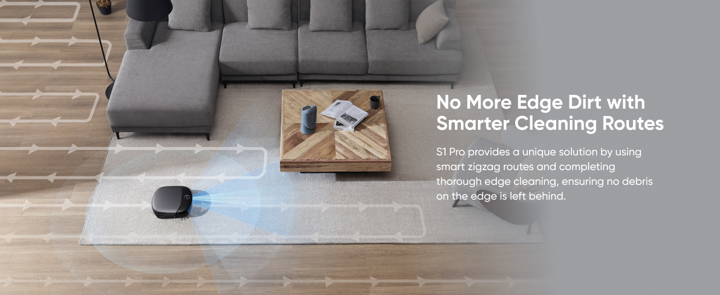 Robotic vacuum cleaner navigating around a gray sectional sofa on hardwood flooring, demonstrating edge-cleaning capability.