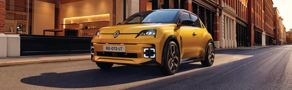 Bright yellow compact car photographed on urban street at sunset/sunrise with brick buildings in background.