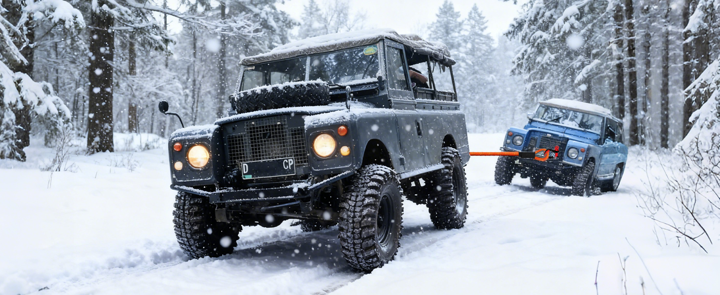 Snow-covered winter scene with multiple vehicles driving through heavy snow conditions, suggesting winter weather or storm situation.