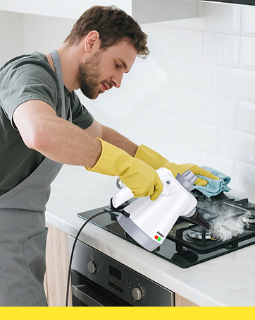 White electric handheld steam cleaner with multiple attachment accessories and nozzles displayed on gray surface.