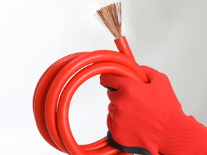 Close-up of red work gloves holding black pliers or cutting tool against a white background.