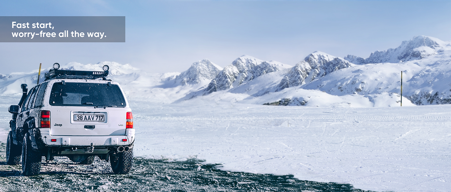 White SUV with roof rack driving on snowy terrain with snow-capped mountains in background. Text reads 'Fast start, worry-free all the way.'