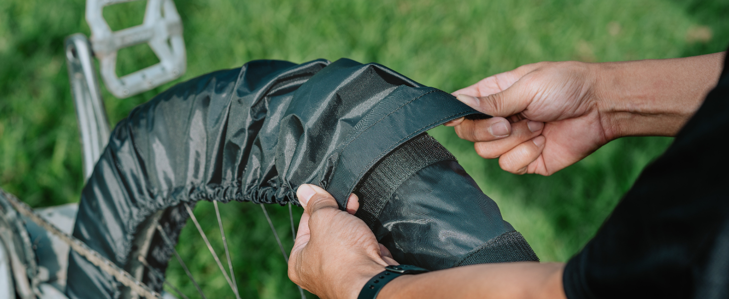 Hands adjusting a dark waterproof or protective cover over what appears to be outdoor furniture or equipment.