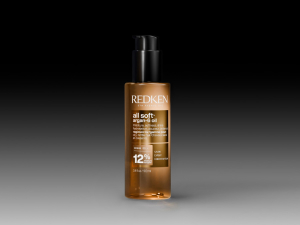 Tan-colored liquid cosmetic product in squeeze tube displayed against black background with dramatic lighting and white shadow reflection below.