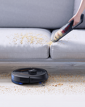 a person cleaning a couch with a vacuum cleaner.