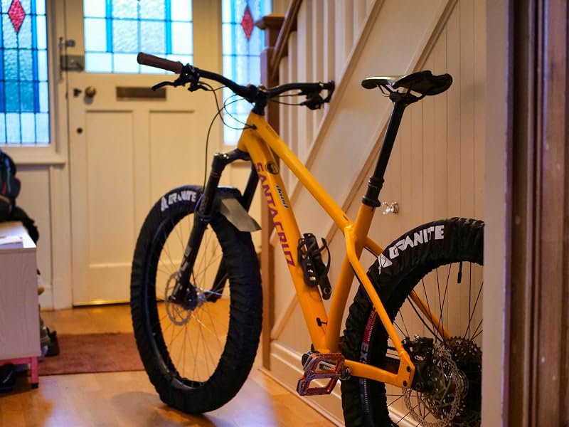 Orange electric fat tire bicycle displayed indoors against white walls and windows. Shows rugged tires, sturdy frame, and modern design elements.