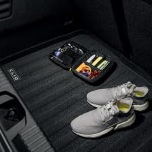 Interior car floor area showing dark carpeted floor mat and metallic door sill trim in low light conditions.