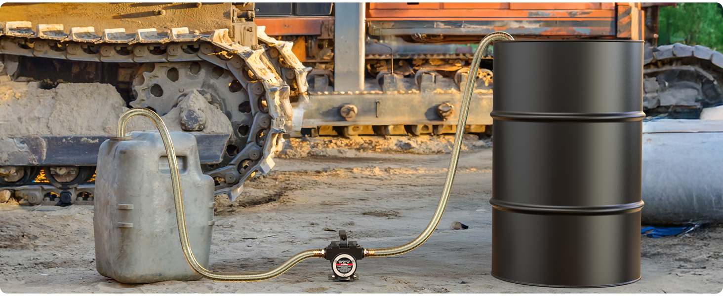 Industrial scene showing metal drums and equipment. Large black oil drums positioned next to smaller metal container with connecting hose or cable between them. Heavy machinery tracks visible in background.