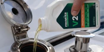 Text reads 'PREMIER' and 'V25' on product bottles. Three clear plastic containers in graduated sizes containing green-labeled industrial or automotive fluid product in white bottles.